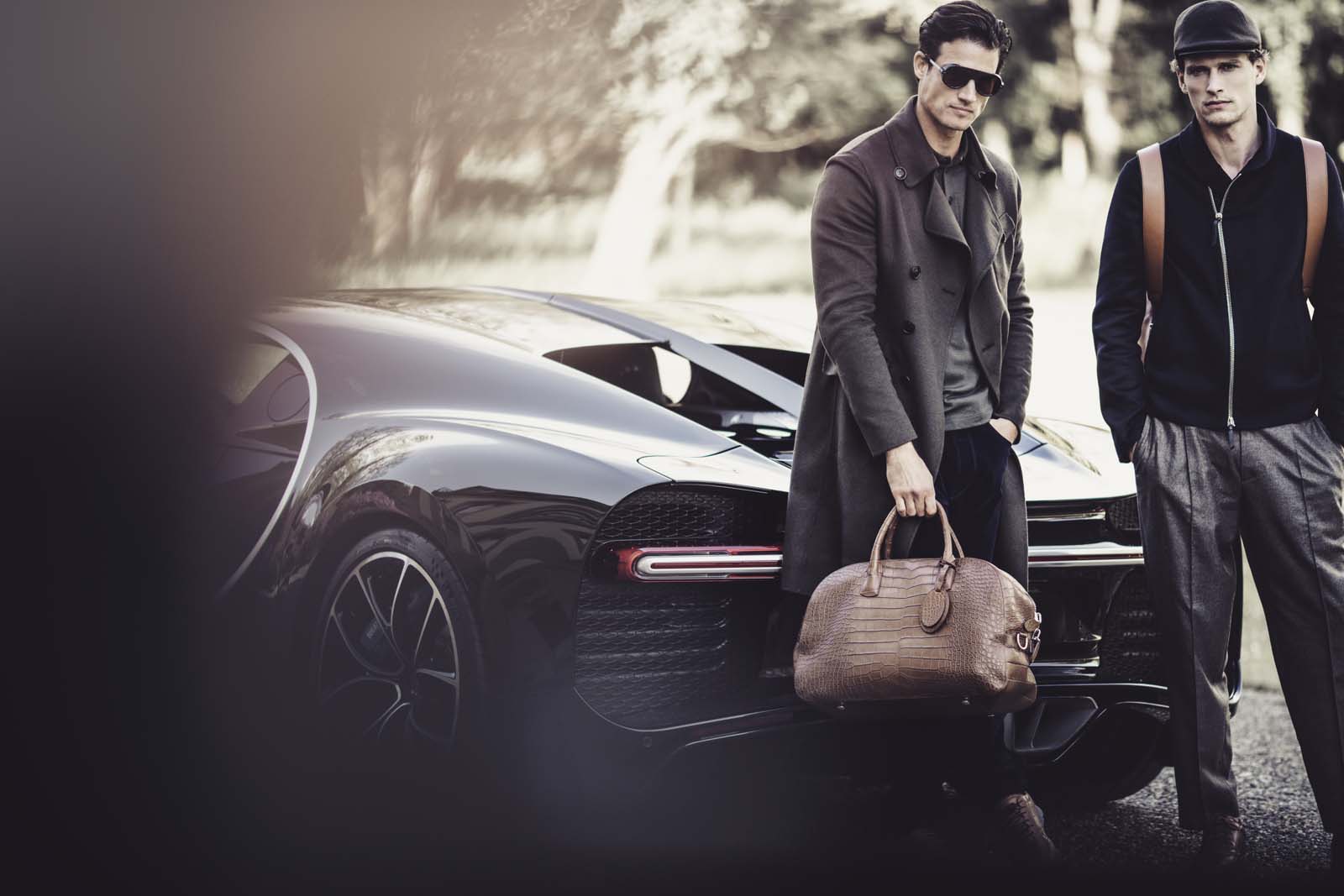 Giorgio Armani male models posing against a black Bugatti supercar