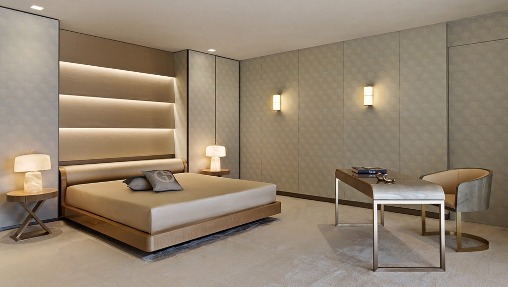 Golden hues hotel bedroom with work desk and chair.