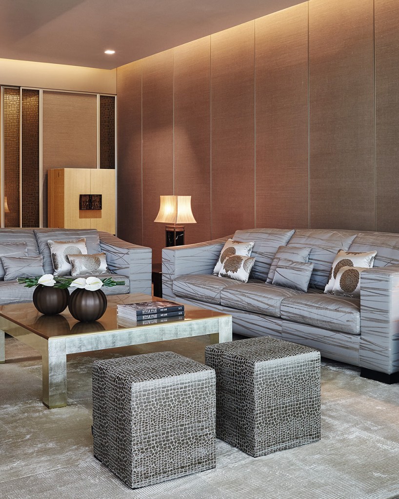 Comtemporary lounge interior with two couches, two cube stools, a coffee table with some books and vases on it.
