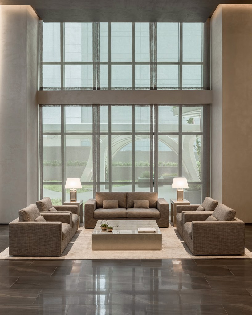 Super high ceilings living room with three armchairs positioned by the low coffee table.