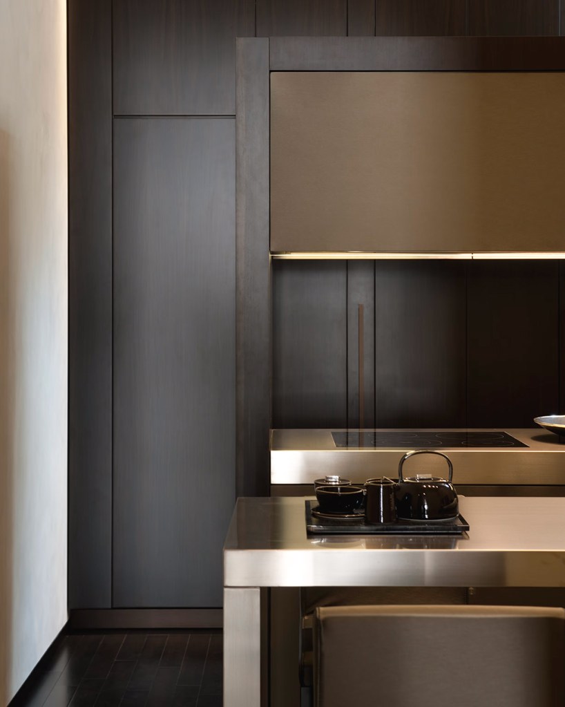 Sleek designer kitchen in dark wood and warm metallic finishings