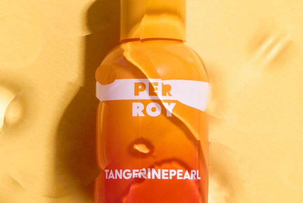 A vibrant orange bottle labeled "PERROY TANGERINE PEARL" stands against a textured, sunny yellow backdrop, exuding a lively and fresh mood.