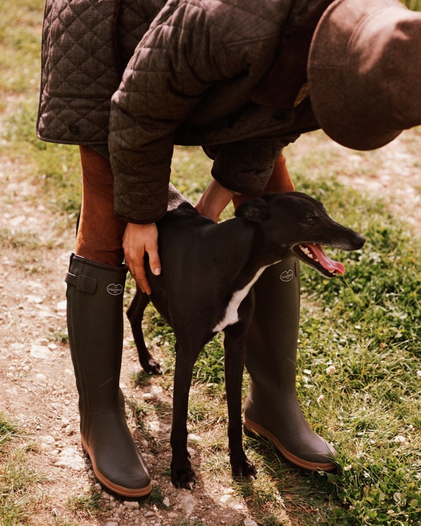 Woman plays with dog wearing brown Loro Piana collection.