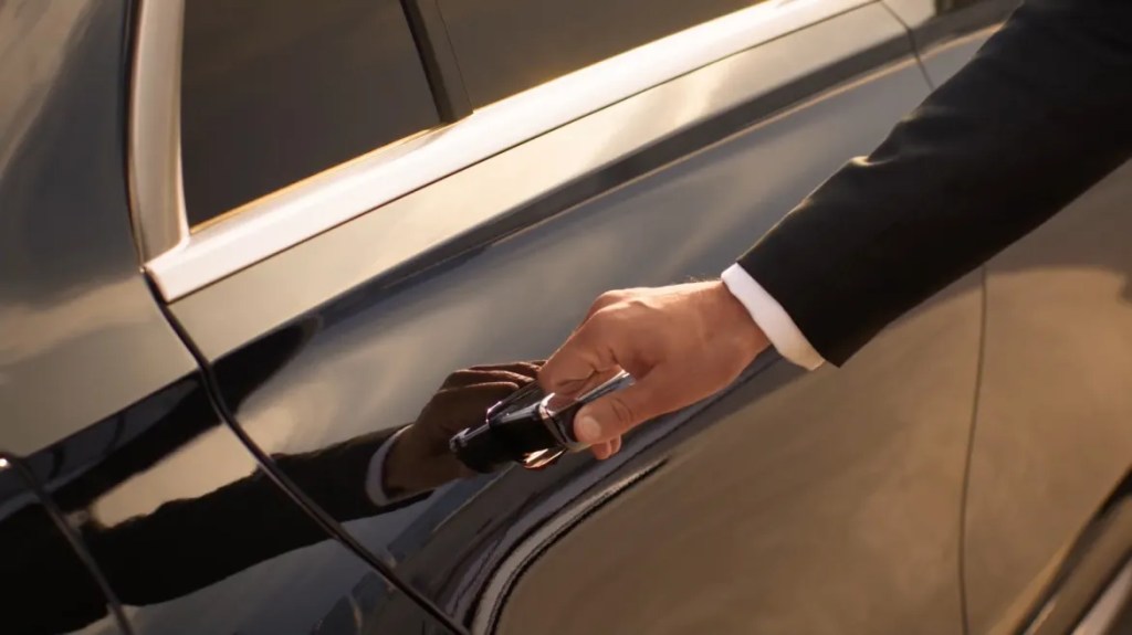 driver's hand opening a door of a luxury wheely transfer car