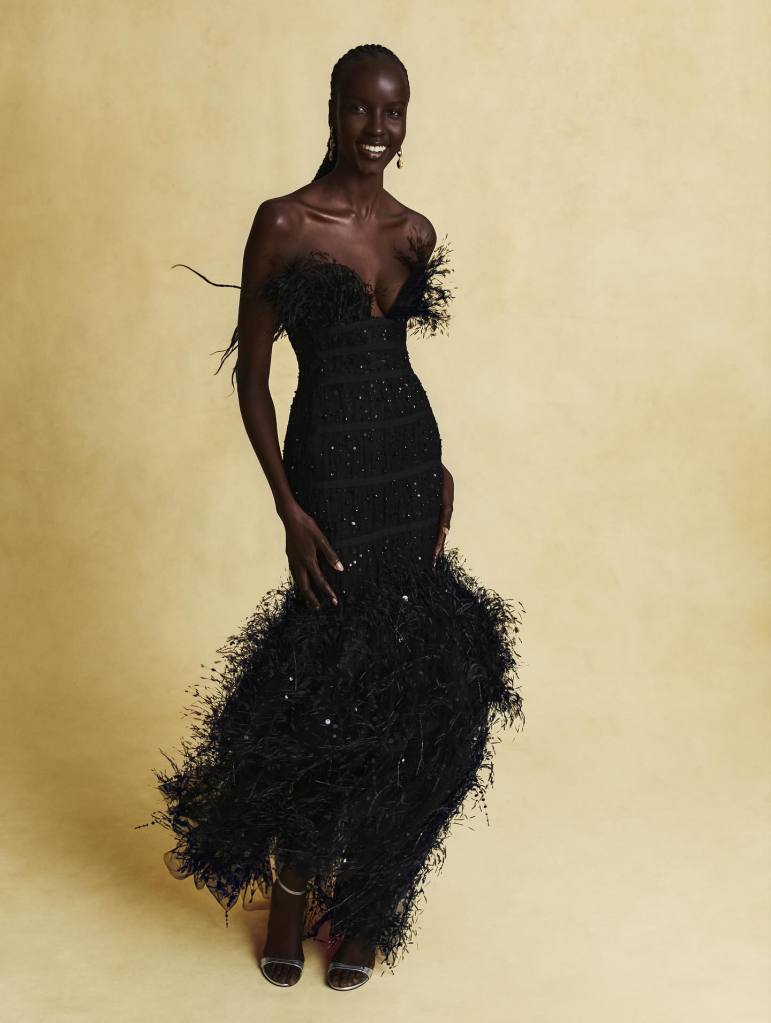 Oscar de la Renta black dress on a black female model smiling against the yellow background