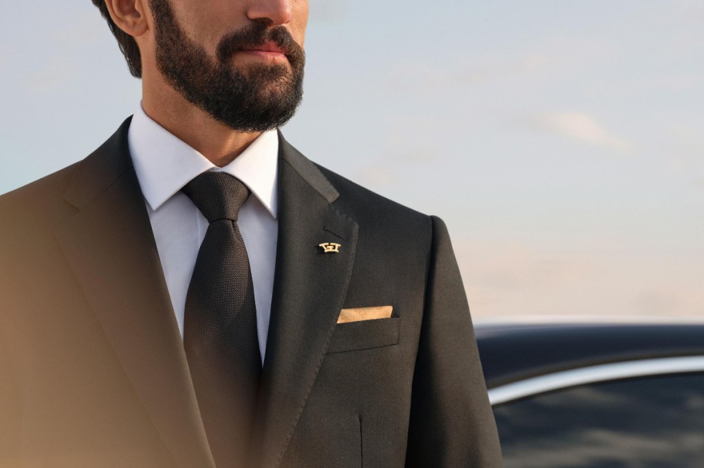 private driver in sober suit with wheely gold badge on his collar