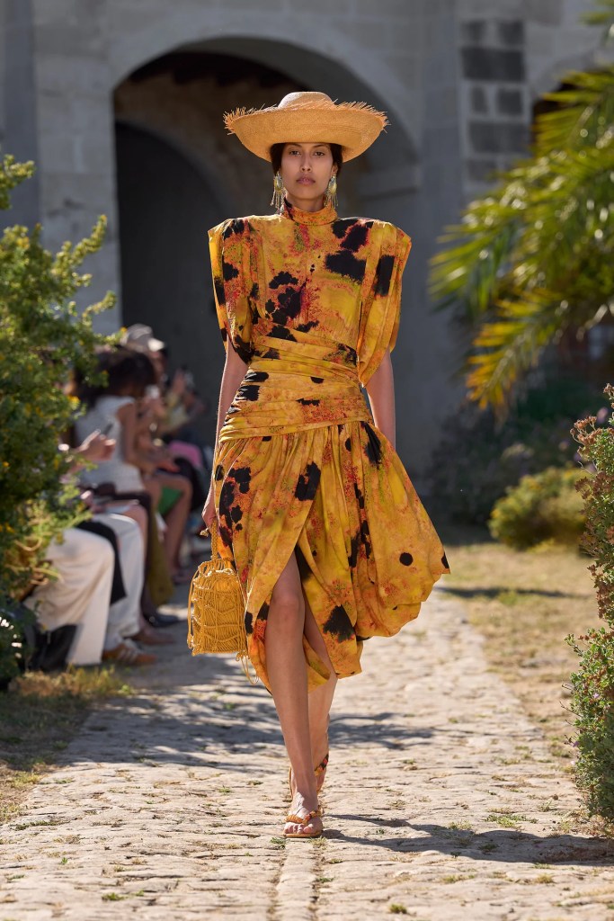 Alémais model wears stunning layered orange dress and a beach hat
