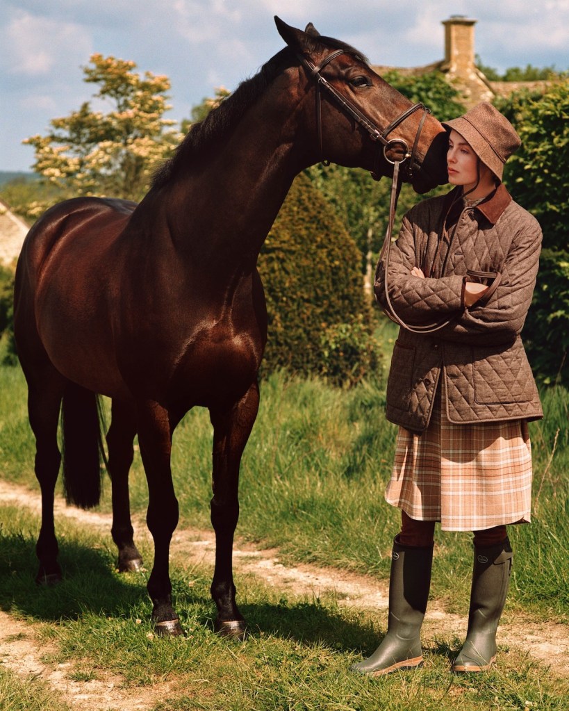 Countryside picture with woman in brown Loro Piana outfit and cocolate coloured horse kissing woman.