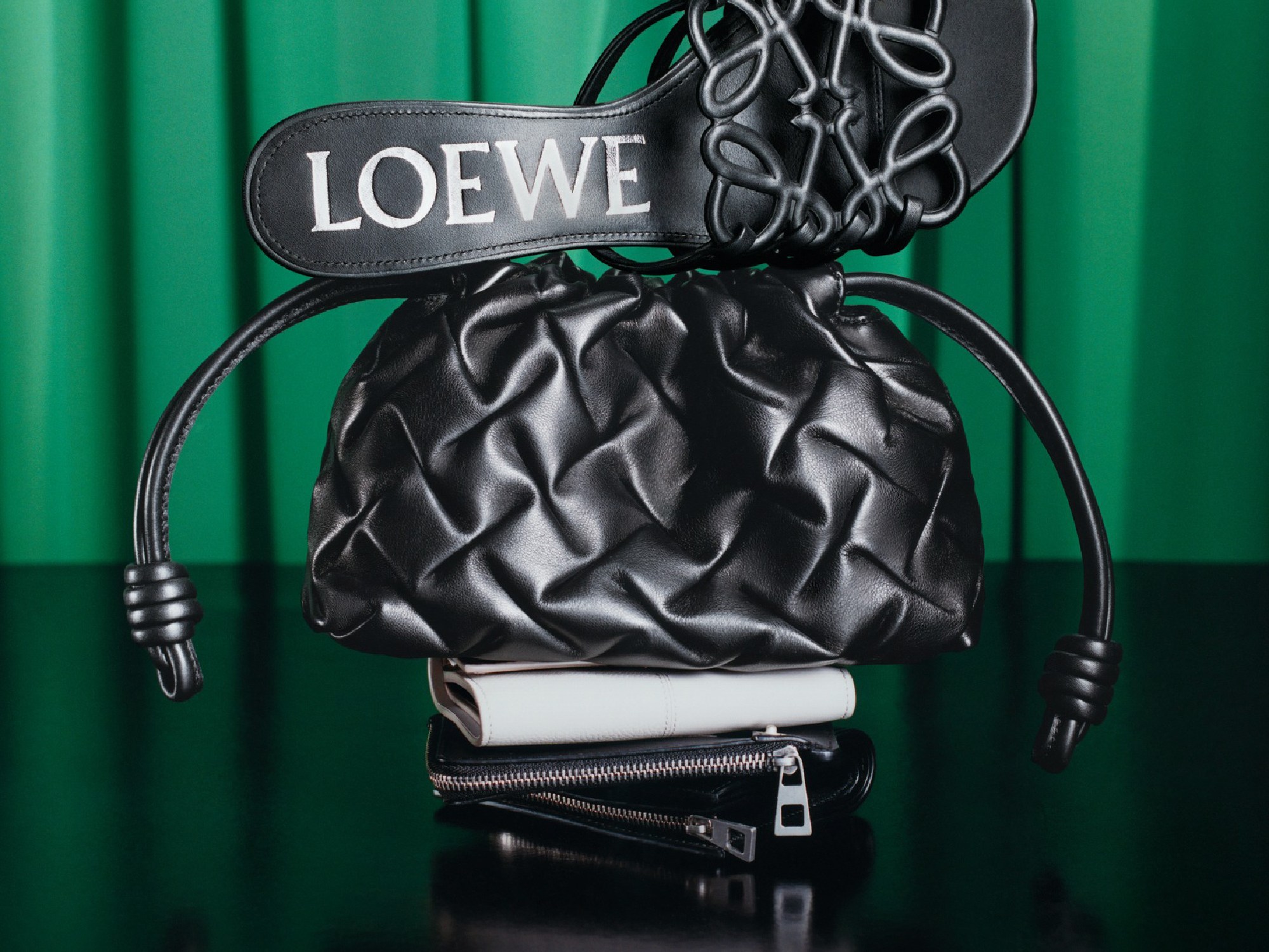 Loewe Ginza fashion accessories: black leather bag and high heel shoe on the green background