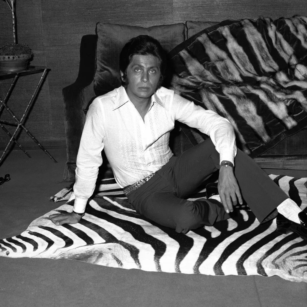 Italian designer Valentino Garavani sitting down on the zebra carpet