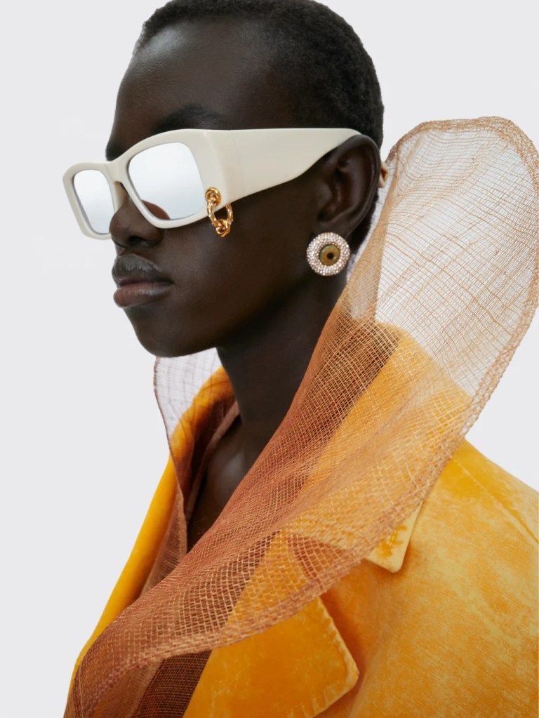 Schiaparelli yellow coat and white sunglasses on a black model