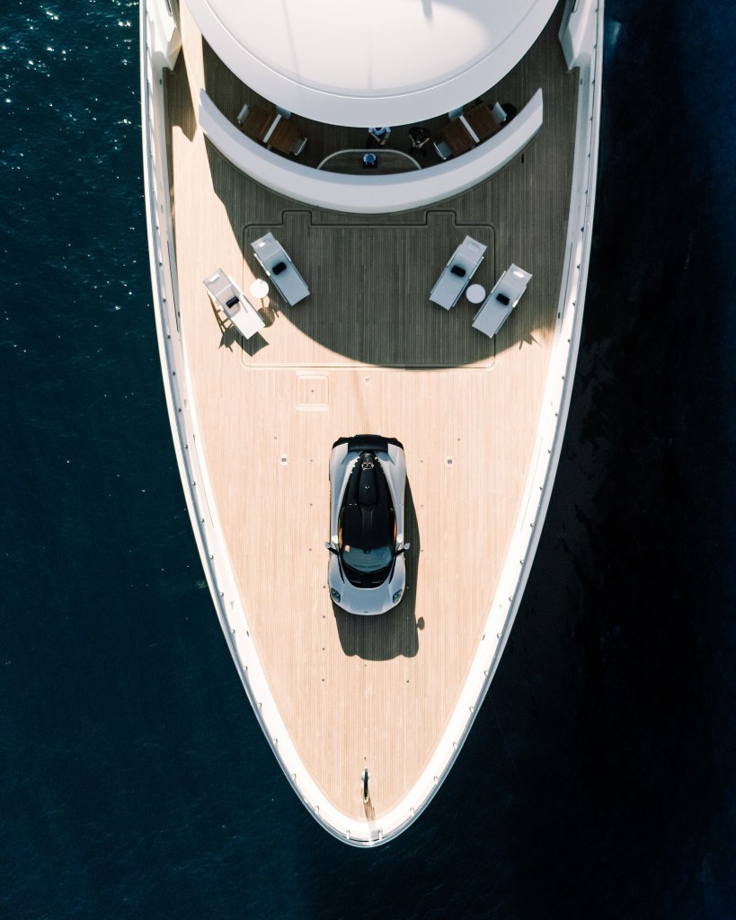 Luxury yacht with hypercar on deck birds eye view